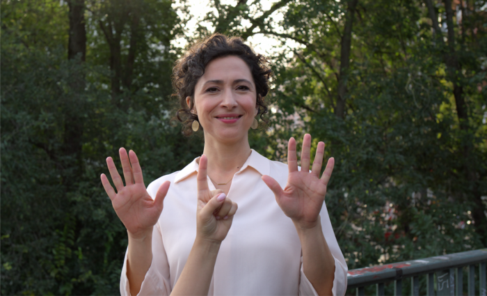 Eine Frau in einem Park, die 11 Finger hebt, um darzustellen, dass die Procredit Bank in 11 L&auml;ndern pr&auml;sent ist.